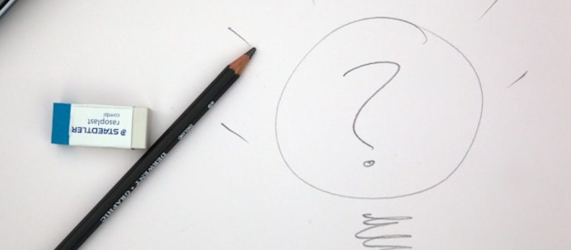 pencil resting against a piece of paper next to a drawn question mark